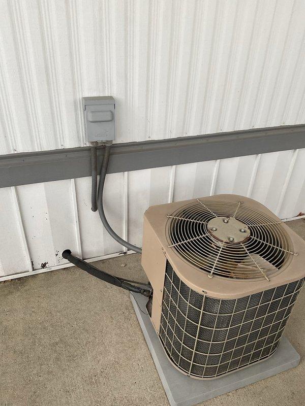 Completed comprehensive estimate for replacement of 2-ton air conditioning system serving mobile home application. Evaluated existing outdoor condensing unit mounted on concrete pad against exterior corrugated metal wall, noting age-related wear and operational degradation. Assessed electrical disconnect box, conduit routing, and power supply configuration. Inspected indoor air handler components including blower motor assembly, gas valve connections, electrical wiring, and cabinet condition to determine compatibility requirements and scope of replacement work necessary for complete system upgrade.
