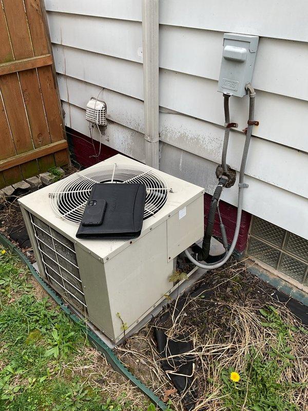 Completed comprehensive estimate for full air conditioning system replacement at residential property. Evaluated existing outdoor condenser unit with beige cabinet and top-discharge fan configuration, currently positioned on concrete pad against exterior wall with electrical disconnect and refrigerant line set in place. Assessed indoor furnace and air handler equipment located in basement utility area, noting existing ductwork configuration and plenum connections. Documented current system specifications, equipment access points, and installation requirements including electrical service, refrigerant line routing through exterior wall penetration, and condensate drainage provisions. Provided detailed replacement options for matching outdoor condensing unit and indoor air handling equipment to ensure proper system sizing and efficiency ratings for the home's cooling requirements.