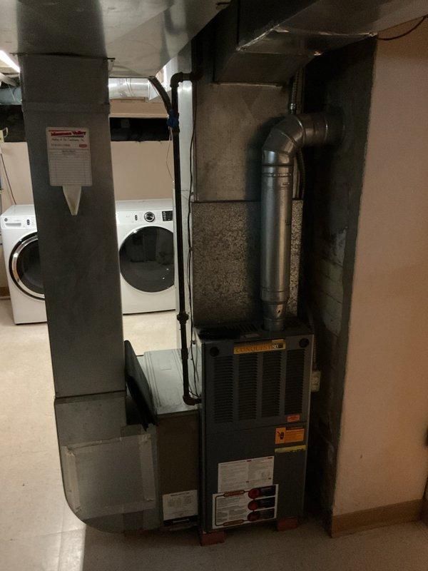 Completed comprehensive estimate for full air conditioning system replacement at residential property. Evaluated existing outdoor condenser unit with beige cabinet and top-discharge fan configuration, currently positioned on concrete pad against exterior wall with electrical disconnect and refrigerant line set in place. Assessed indoor furnace and air handler equipment located in basement utility area, noting existing ductwork configuration and plenum connections. Documented current system specifications, equipment access points, and installation requirements including electrical service, refrigerant line routing through exterior wall penetration, and condensate drainage provisions. Provided detailed replacement options for matching outdoor condensing unit and indoor air handling equipment to ensure proper system sizing and efficiency ratings for the home's cooling requirements.