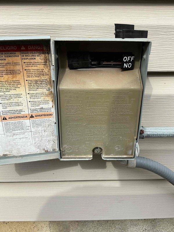 Responded to service call for residential air conditioning system with no cooling condition. Upon arrival, performed visual inspection of 20-year-old AC unit exterior components. Accessed electrical disconnect box mounted on building exterior and documented condition of disconnect switch and internal wiring. Opened control panel enclosure to inspect electrical connections, control board, and associated wiring harness. Found multiple wire connections to central control module with signs of age-related wear and deterioration. Noted disorganized wiring configuration and evidence of dust accumulation throughout electrical compartments. Photographed disconnect box components, warning labels, and internal control panel wiring for documentation purposes. Given the advanced age of the system and observed condition of electrical components, provided customer with assessment of unit status and discussed available options for repair versus replacement considerations.