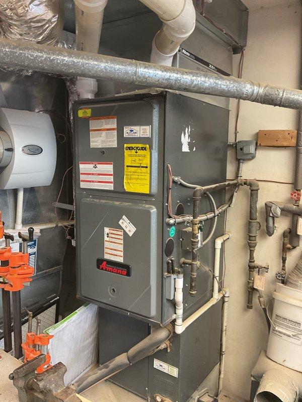 Conducted comprehensive on-site assessment of existing Amana furnace system located in basement mechanical room to provide replacement estimate. Evaluated current equipment configuration including integrated humidifier unit, ductwork connections, hydronic piping network with copper and PVC components, electrical supply, and ventilation systems. Documented existing installation through detailed photography of interior mechanical room setup and exterior utility connections on brick structure. Assessment included review of current system capacity, venting requirements, condensate drainage pathways, and compatibility with existing infrastructure to determine optimal replacement specifications and installation requirements.