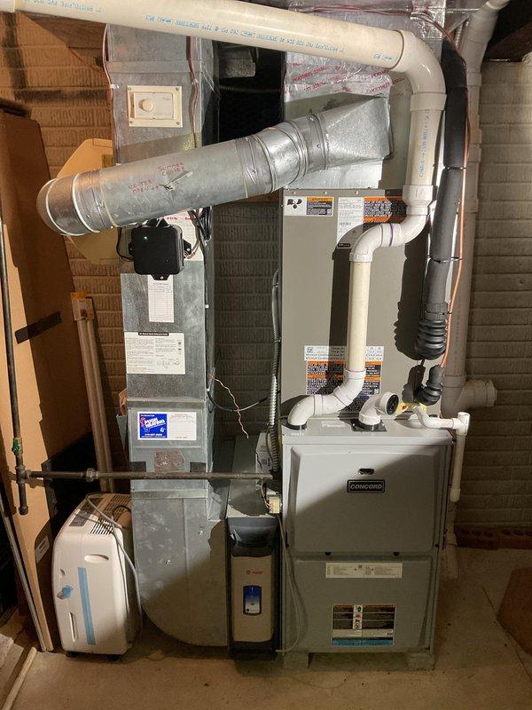 Completed full HVAC system installation including a 14 SEER 3.5-ton air conditioning condensing unit with matching evaporator coil. Installed new 7/8" x 50' refrigerant line set connecting the outdoor condensing unit to the indoor coil mounted on the existing Concord furnace. Positioned condensing unit on new concrete pad against exterior wall with decorative rock landscaping for proper drainage and clearance. Installed new electrical disconnect box and whip for code-compliant power supply to the condensing unit. Mounted L-40 thermostat to control the new cooling system. All refrigerant lines were properly insulated and secured. Electrical connections were completed per manufacturer specifications and local code requirements. System was pressure tested for leaks, evacuated, and charged with appropriate refrigerant to manufacturer specifications. Verified proper airflow, temperature differential, and system operation. All components functioning as designed with proper drainage establish
