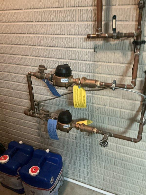 Responded to service call for leaking tanked water heater that was recently installed by another contractor and still under warranty period. Upon inspection, identified leak source in the plumbing connections associated with the water heater system. The installation included an expansion tank, copper piping with multiple bends and connections, circulation pump components, and backflow prevention devices mounted on the brick wall. Documented the existing installation configuration with photographs showing the expansion tank, copper pipe routing, soldered joints, and associated plumbing components for warranty claim purposes. Verified proper installation of expansion tank with metal mounting straps and assessed the overall system layout including the PVC connections and circulation equipment. Recommended contacting the original installing contractor to address the leak under the existing warranty coverage.