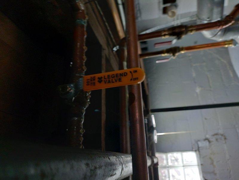 Responded to service call for boiler system with reported leak from pipe above unit. Upon inspection, identified active water leak at copper piping connection near boiler assembly, specifically at valve body with multiple pipe branches. Documented existing plumbing configuration including Legend valve assembly and associated copper piping infrastructure for further assessment and repair recommendations.