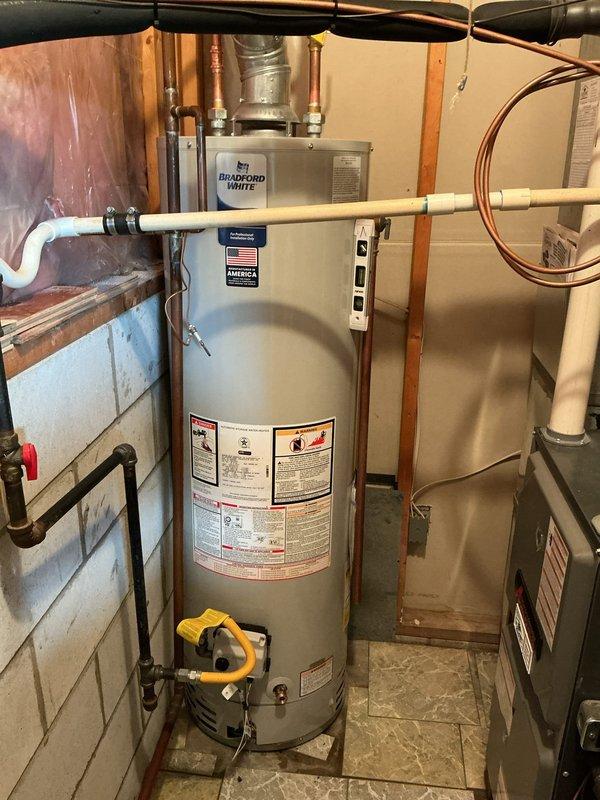 Conducted on-site assessment of existing water heater system in basement utility area for replacement estimate. Evaluated current gas-fired water heater installation, including connections to gas supply line with yellow T-handle shut-off valve, existing copper plumbing connections, and galvanized metal venting system with flexible duct transition. Documented configuration of surrounding mechanical systems including proximity to HVAC equipment and available workspace for replacement unit. Photographed current installation showing water heater positioning, venting arrangement through wooden framing, copper supply lines with brass fittings, and basement infrastructure to provide accurate replacement specifications and installation requirements.