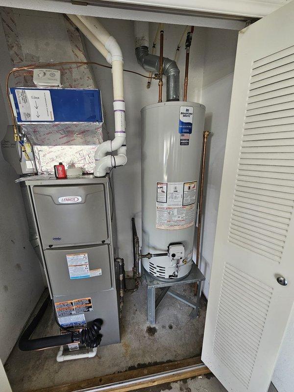 Installed 40-gallon tall tanked water heater in residential utility closet with proper expansion tank, copper supply lines, and PVC venting. Connected all hot and cold water lines with brass fittings, installed pressure relief valve with discharge piping, and secured unit on elevated platform alongside existing Lennox furnace. System tested and operational with no leaks detected.