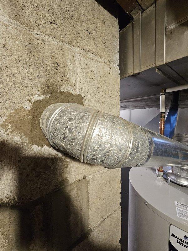 Completed installation of a 50-gallon Bradford White tanked water heater in basement utility area. Unit was properly positioned on concrete floor with all copper supply lines, fittings, and safety valves connected according to manufacturer specifications and local plumbing codes. All connections were tested and verified operational.
