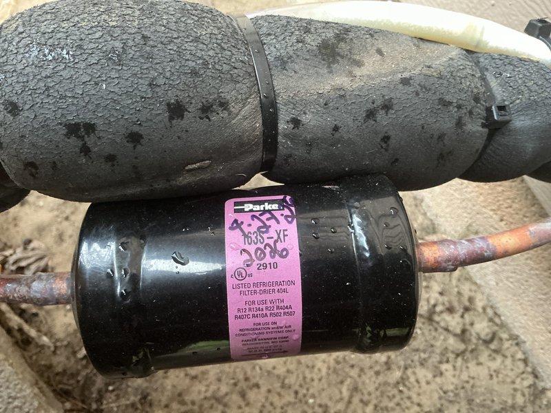 Responded to air conditioning repair call and performed system diagnostics. Upon inspection, discovered severely corroded copper refrigerant lines at the condenser coil connection points, exhibiting heavy oxidation and deterioration that compromised system integrity. The refrigerant tubing showed significant weathering with mottled patina throughout, particularly at joint locations where leaks were likely occurring.

Replaced failed filter-drier assembly with new Parker 404L model compatible with system refrigerant type. Addressed compromised refrigerant lines by cutting out corroded sections and installing new copper tubing with proper brazing techniques. Repaired connections at condenser coil to ensure leak-free operation. Pressure tested system to verify integrity of all repairs and connections. Evacuated system to proper vacuum levels, then recharged with appropriate refrigerant to manufacturer specifications. Verified proper system operation with temperature differential readings 