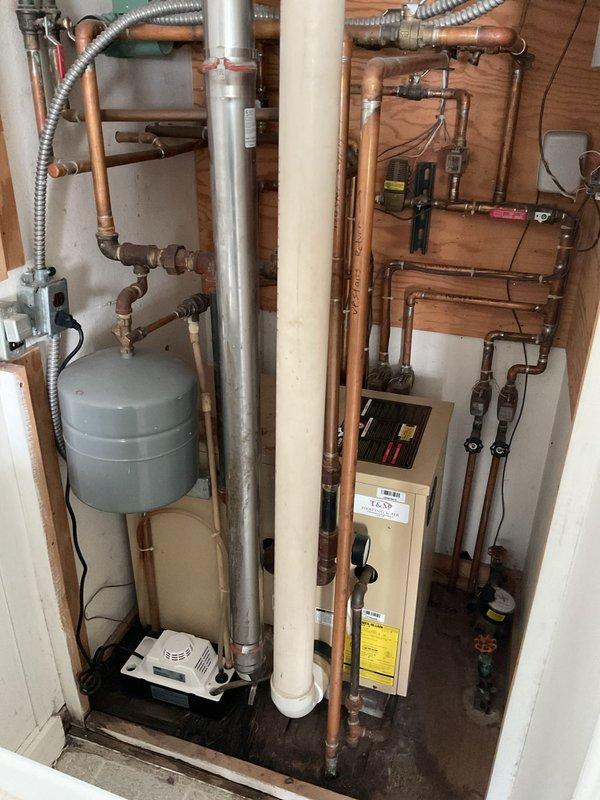 Completed comprehensive boiler system estimate for existing hydronic heating installation featuring expansion tank, multi-zone copper piping network, and integrated water heating components. Documented current system configuration including PVC venting, zone valving, control mechanisms, and all mechanical connections to provide accurate replacement specifications and equipment recommendations.