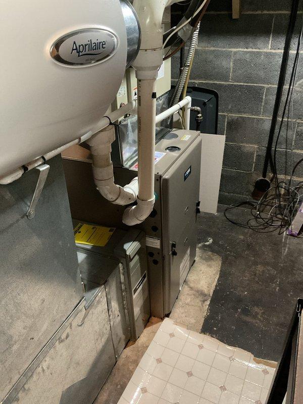 Conducted comprehensive assessment of existing HVAC system for complete air conditioning replacement. Evaluated outdoor Bryant XC 1000 condensing unit positioned on exterior pad against residential brick wall, documenting current equipment specifications and installation conditions. Inspected indoor air handler and associated components in basement mechanical room, including existing Aprilaire whole-house humidifier, ductwork connections, and refrigerant line routing through concrete block foundation. Photographed equipment nameplate data, electrical connections, and mechanical room layout to develop accurate replacement specifications. Assessed accessibility for equipment removal and new installation, noting exterior clearances around outdoor unit and basement workspace constraints. Documented refrigerant line penetrations, condensate drainage routing, and existing electrical service to outdoor unit. Prepared detailed estimate for complete air conditioning system replacement including