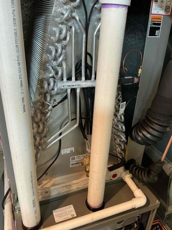 Responded to call back on recent AC installation that failed inspection due to condensation leaking into furnace cabinet. Upon arrival, inspected evaporator coil assembly and drainage system. Found improperly pitched or clogged condensate drain line allowing water to overflow from drain pan into furnace cabinet. Cleared drain line obstruction, verified proper pitch and drainage flow, and confirmed condensate is now routing correctly away from unit. Tested system operation and verified no moisture intrusion into cabinet.