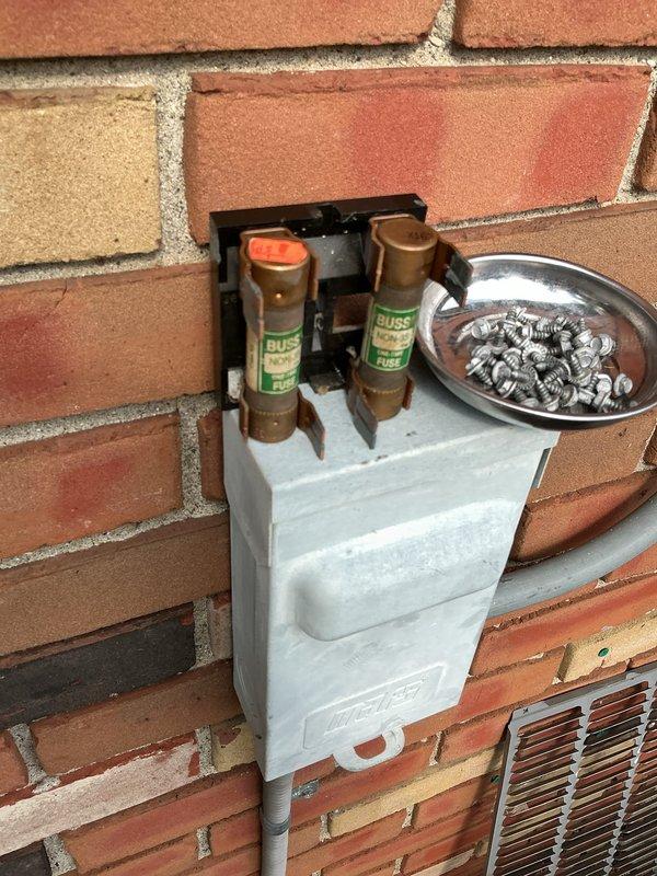 Performed routine cooling maintenance on a 5-year-old air conditioning system. Inspected outdoor disconnect box and fuse assembly, confirming proper electrical connections and fuse integrity. Examined rooftop condensing unit installation, verified secure mounting, checked refrigerant lines and electrical conduit routing through decorative rock ballast area. All components found in good working condition with normal wear for unit age.
