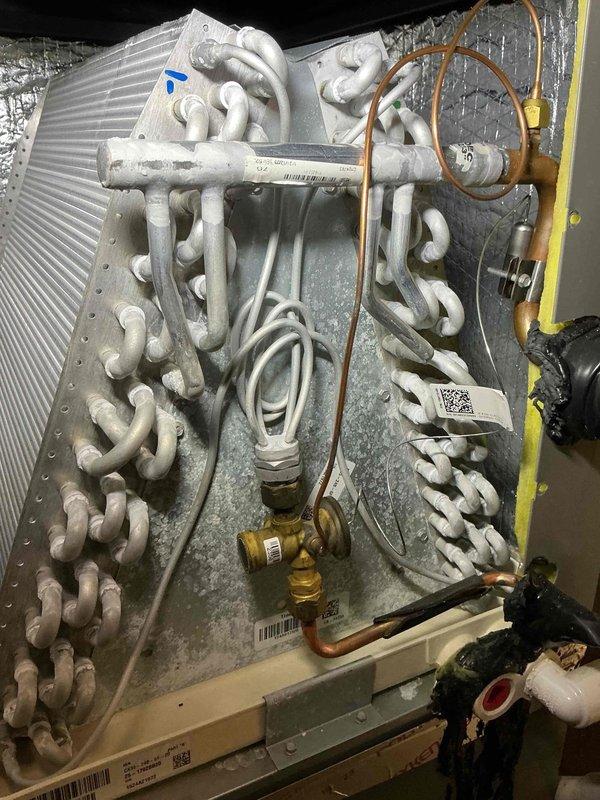 # HVAC Service Completed

Performed air conditioning tune-up and system inspection. Upon arrival, discovered extensive ice buildup on the evaporator coil assembly, indicating restricted airflow or refrigerant issues. Documented frozen coil condition with exterior and interior inspection camera photographs showing crystallized frost across serpentine tubing and base plate. Inspected copper refrigerant lines, brass fittings, and service valves for leaks or damage. Used borescope to examine internal coil fins and verify extent of icing throughout the heat exchanger. System requires further diagnosis to determine root cause of freezing condition, which may include low refrigerant charge, restricted airflow from dirty filter, or blower motor malfunction.