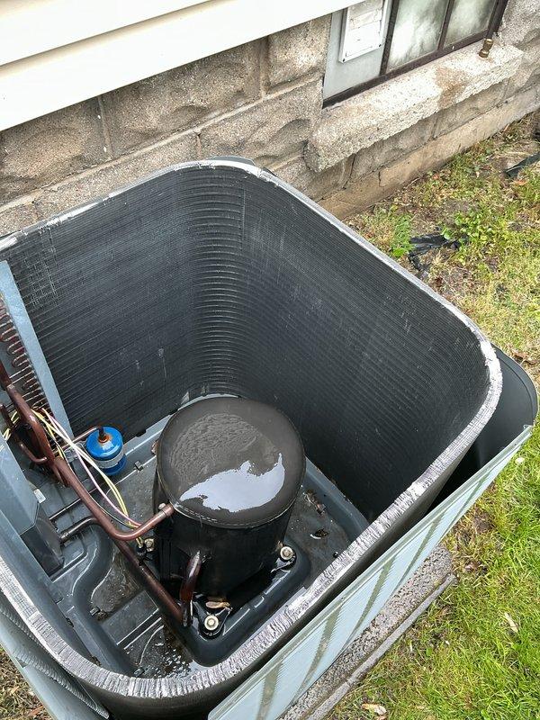 Performed routine maintenance on 13-year-old residential air conditioning system. Inspected outdoor condenser unit with protective guard, verified refrigerant line connections and insulation integrity, and conducted diagnostic measurements using digital testing equipment in mechanical space. Unit operating within normal parameters with no immediate service needs identified.