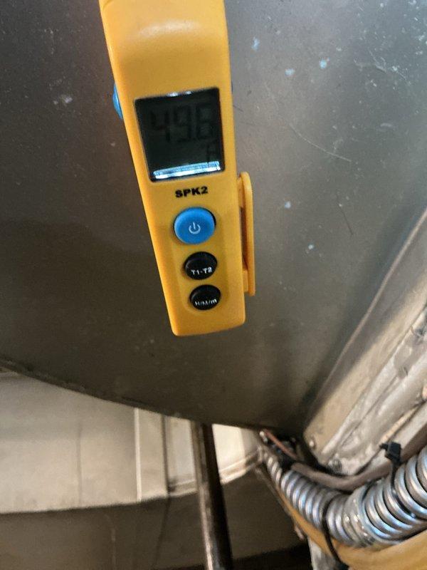 Performed routine maintenance on 13-year-old residential air conditioning system. Inspected outdoor condenser unit with protective guard, verified refrigerant line connections and insulation integrity, and conducted diagnostic measurements using digital testing equipment in mechanical space. Unit operating within normal parameters with no immediate service needs identified.