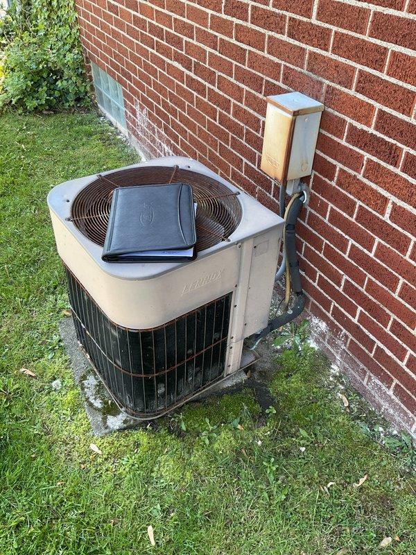 Completed comprehensive HVAC system evaluation for rental property replacement estimate. Assessed existing Lennox Pulse furnace installation in basement utility area, documenting current equipment configuration including ductwork, venting system, condensate drainage with safety float switch, and electrical connections. Evaluated outdoor air conditioning unit positioned on concrete pad against exterior brick wall, noting electrical disconnect box and refrigerant line connections to determine complete system replacement requirements and specifications.