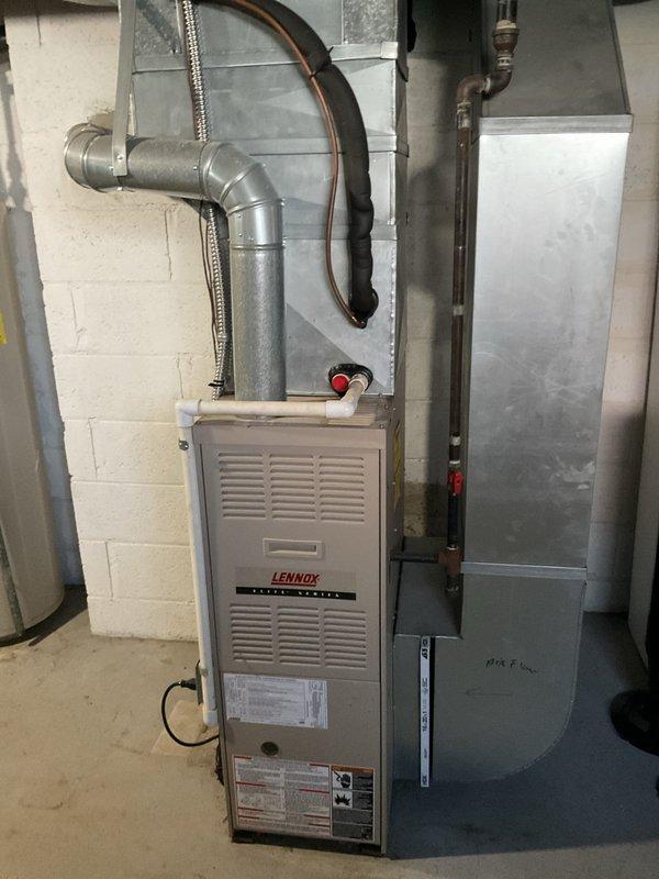 Completed comprehensive HVAC system evaluation for rental property replacement estimate. Assessed existing Lennox Pulse furnace installation in basement utility area, documenting current equipment configuration including ductwork, venting system, condensate drainage with safety float switch, and electrical connections. Evaluated outdoor air conditioning unit positioned on concrete pad against exterior brick wall, noting electrical disconnect box and refrigerant line connections to determine complete system replacement requirements and specifications.