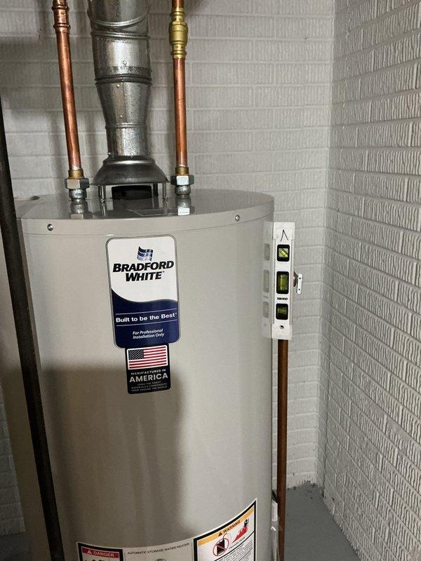 Responded to service call for 26-year-old Bradford White gas water heater experiencing active leak. Upon inspection, confirmed unit had exceeded its expected service life and was no longer functioning reliably. Documented existing installation configuration including copper supply line connections, galvanized vent piping, and gas valve assembly with control unit mounted to tank exterior. Photographed current setup showing top connections with brass fittings, flue arrangement, and overall equipment condition in basement utility area. Provided customer with comprehensive quote for complete water heater replacement including new gas-fired unit, necessary code-compliant connections, and proper venting system to resolve ongoing leak issue and restore hot water service.
