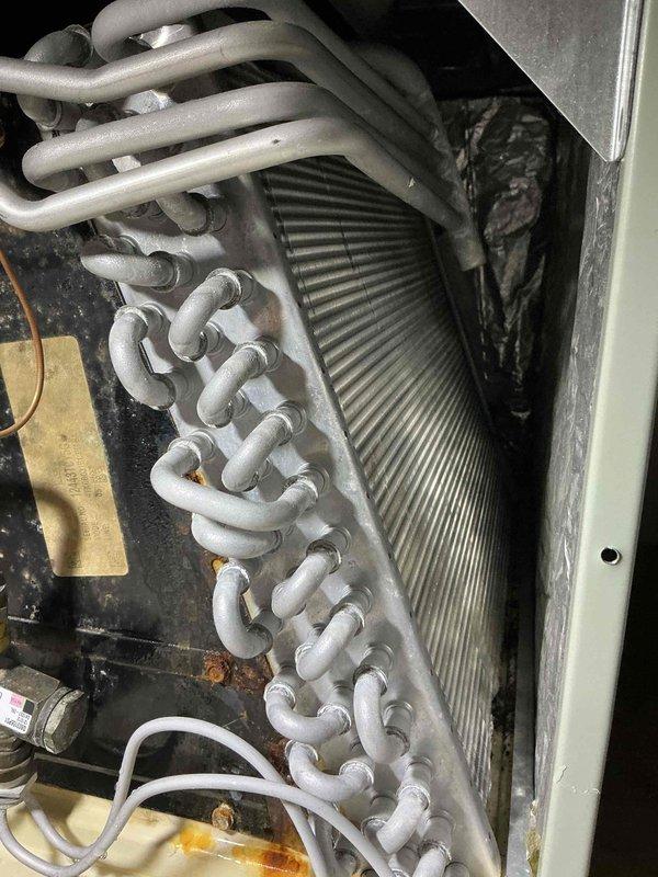 # HVAC Maintenance - Cooling Service

Performed comprehensive annual maintenance on a 13-year-old residential air conditioning system. Upon arrival, conducted visual inspection of outdoor condenser unit, noting accumulated dirt and debris on spiral-finned condenser coil and signs of age-related wear on components.

**Outdoor Unit Service:**
- Inspected condenser unit positioned on concrete pad adjacent to residence
- Evaluated condition of spiral-ribbed condenser coil, identifying significant dirt accumulation in fin grooves
- Cleaned condenser coil thoroughly to restore optimal heat transfer efficiency
- Checked refrigerant lines and electrical connections for integrity
- Verified proper operation of condenser fan motor
- Inspected electrical disconnect and service panel mounted on exterior wall
- Evaluated mounting platform and concrete pad condition
- Confirmed adequate clearance around unit for proper airflow

**Indoor Unit Service:**
- Accessed evaporator coil assembly and serpent