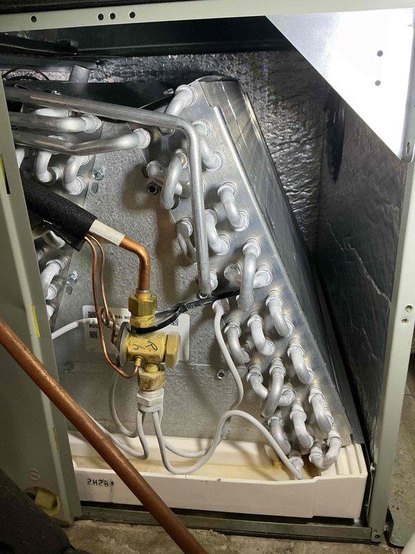 # HVAC Maintenance - Cooling System Service

Performed comprehensive preventive maintenance on a 4-year-old residential air conditioning system. Conducted thorough inspection of all major components including evaporator coil assembly, blower motor, electrical control panel, and refrigerant system connections.

Inspected evaporator coil for cleanliness and proper airflow, noting aluminum finned coil tubes in good condition with no visible debris accumulation or damage. Examined brass service valve assembly and verified refrigerant line connections for proper sealing and absence of leaks. Checked copper refrigerant lines for signs of wear, corrosion, or oil staining.

Opened electrical control panel and inspected all internal wiring, connections, and components. Verified proper wire terminations with secure wire nuts and twist connectors throughout the system. Examined capacitors mounted to blower motor assembly, confirming labels were legible and units showed no signs of bulging, leakin