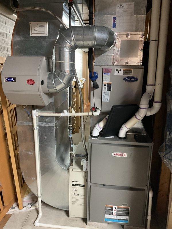 Completed comprehensive AC replacement estimate for residential property. Evaluated existing indoor HVAC system located in basement utility area, including Carrier furnace, Lennox air handler, metal ductwork configuration, and associated white PVC ventilation piping. Assessed outdoor Carrier condenser unit positioned on concrete pad adjacent to home exterior with existing electrical conduit routing through vinyl siding. Photographed and documented current system components, installation layout, ductwork connections, and equipment specifications to provide accurate replacement proposal for complete air conditioning system upgrade.