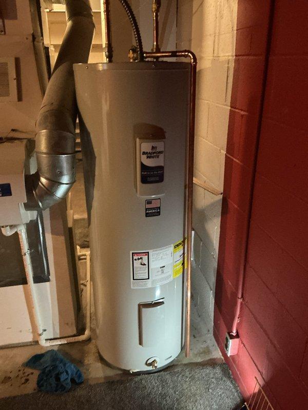 Installed a 50-gallon Bradford White electric water heater in basement utility area. Connected hot and cold water supply lines using copper piping with brass compression fittings, installed temperature and pressure relief valve with discharge piping, and completed electrical connections to power the unit. Verified all connections for proper operation and tested system functionality upon completion.