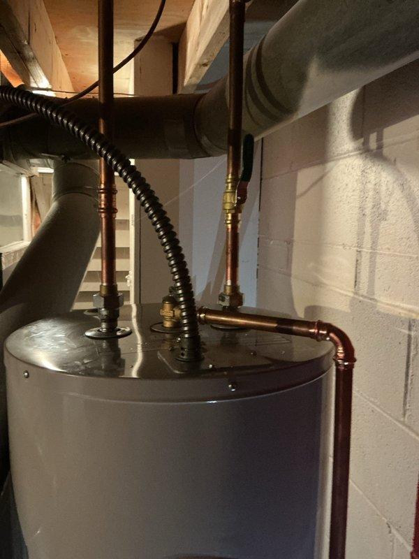Installed a 50-gallon Bradford White electric water heater in basement utility area. Connected hot and cold water supply lines using copper piping with brass compression fittings, installed temperature and pressure relief valve with discharge piping, and completed electrical connections to power the unit. Verified all connections for proper operation and tested system functionality upon completion.
