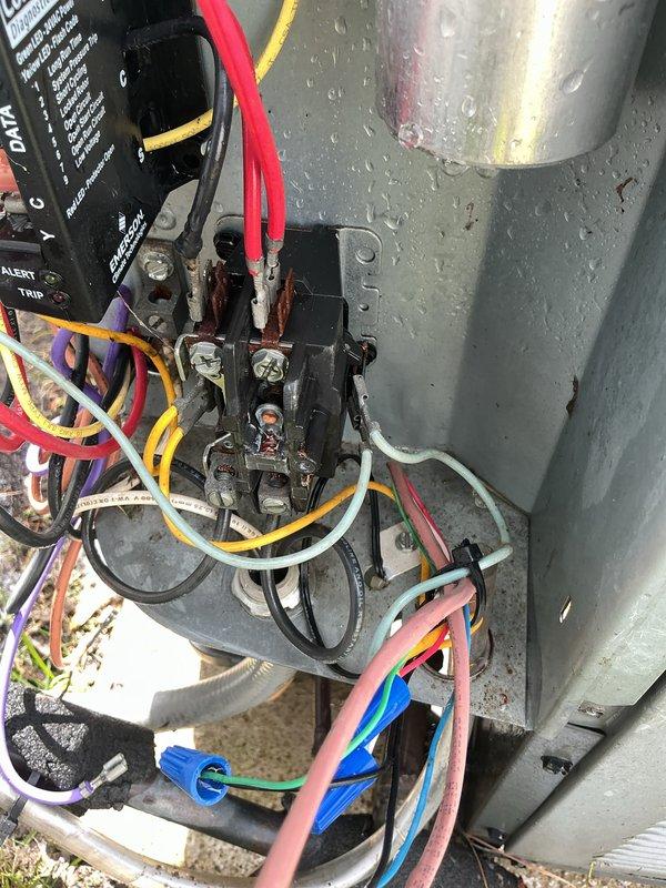 Completed MVP cooling maintenance on 14-year-old air conditioning system during scheduled 1-5 PM service window with advance call ahead notification. Performed comprehensive inspection of outdoor condensing unit and indoor air handler components, documenting equipment condition through photographic records. Electrical connections at contactor assembly showed visible corrosion and oxidation on terminal screws and mounting hardware, consistent with age of system. Verified all wire connections including high-voltage and low-voltage circuits, with multiple conductor terminations secured via wire nuts. Inspected capacitor, contactor relay, and control board functionality, noting ALERT and TRIP indicator status. Indoor air handler inspection included examination of blower motor connections, capacitor wiring, and internal components. System operating in humid environment as evidenced by condensation present on equipment surfaces during service visit.