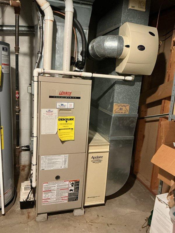 Responded to no cooling call on 20-year-old residential air conditioning system. Upon arrival, confirmed unit would not power on and performed diagnostic inspection of both indoor and outdoor components. Inspected Lennox furnace and air handler assembly in basement, checked electrical connections, verified thermostat communication, and examined recent service history indicating previous part replacement. Evaluated system age and operational status, documented equipment condition with photos of furnace, ductwork, and Aprilaire air cleaner installation. Provided customer with findings and recommendations for system repair or replacement given the advanced age of the equipment.