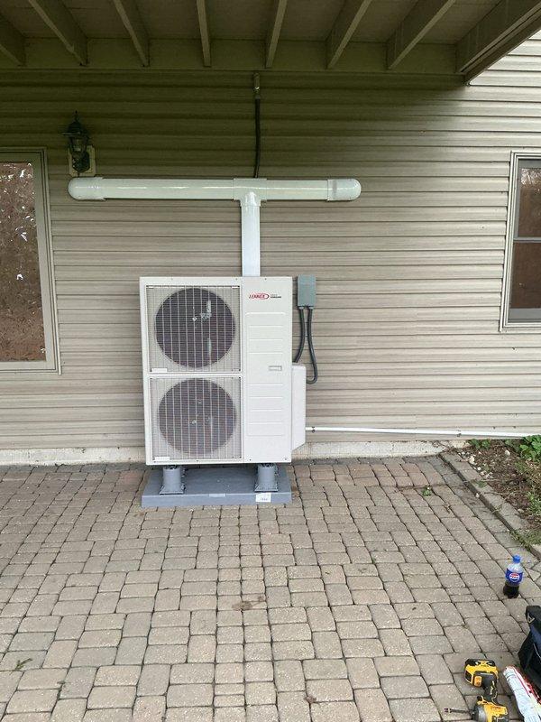 Installed Lennox multi-zone cold climate mini split system with outdoor heat pump unit mounted on new equipment pad with pump ups on exterior brick paver patio. Installed 1/2 ton wall mount head in bedroom positioned right of window at frame height and 1.5 ton wall mount head in common area left of slider at frame height. Ran approximately 20 feet of line set in speed channel slim duct on exterior with tee configuration and termination ends. Routed condensate lines through slim duct. Installed new 40 amp electrical circuit with approximately 100 feet of #8 wire run through grid ceiling to outdoor unit with LB conduit fitting for exterior penetration, connecting to electrical panel located in rear garage area. All indoor units mounted, refrigerant lines connected, electrical connections completed, and system tested for proper operation.