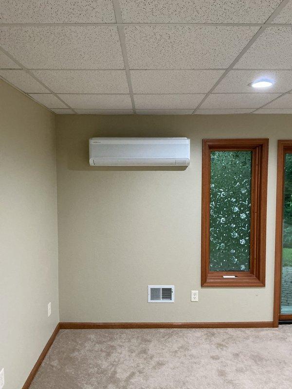 Installed Lennox multi-zone cold climate mini split system with outdoor heat pump unit mounted on new equipment pad with pump ups on exterior brick paver patio. Installed 1/2 ton wall mount head in bedroom positioned right of window at frame height and 1.5 ton wall mount head in common area left of slider at frame height. Ran approximately 20 feet of line set in speed channel slim duct on exterior with tee configuration and termination ends. Routed condensate lines through slim duct. Installed new 40 amp electrical circuit with approximately 100 feet of #8 wire run through grid ceiling to outdoor unit with LB conduit fitting for exterior penetration, connecting to electrical panel located in rear garage area. All indoor units mounted, refrigerant lines connected, electrical connections completed, and system tested for proper operation.