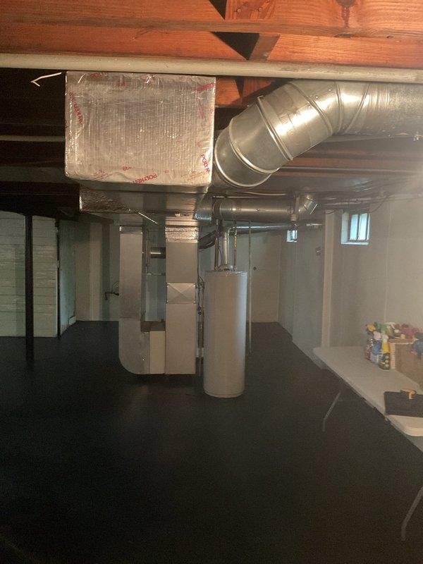 Completed comprehensive AC estimate for full HVAC system replacement in residential basement installation. Evaluated existing Carrier furnace unit, ductwork configuration, and overall heating and cooling infrastructure to provide replacement recommendations. Documented current system layout including vertical furnace positioning, black ductwork distribution across ceiling joists, and integration with existing water heater placement for proper spacing and clearance requirements in utility area.