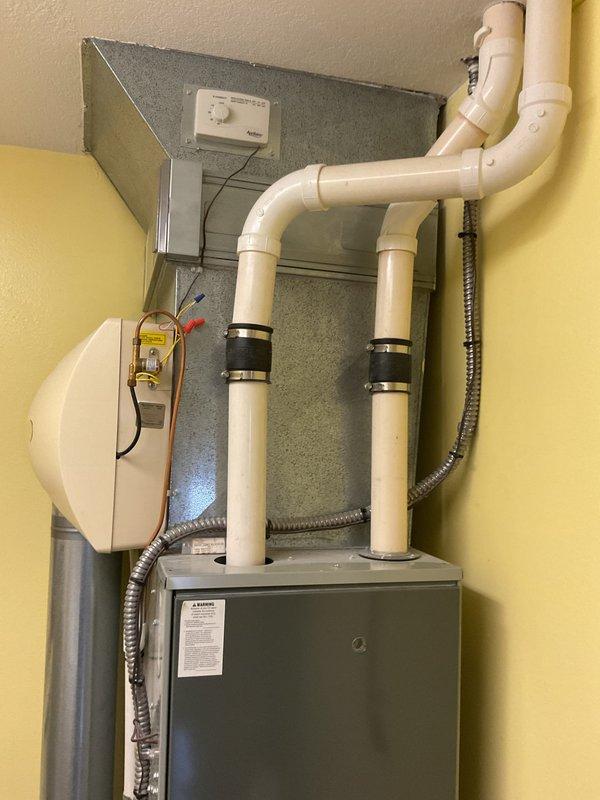 Completed comprehensive HVAC system evaluation for equipment replacement in residential utility closet. Assessed existing Trane XL80i air handler unit, associated venting infrastructure including dual white PVC exhaust pipes with proper coupling bands, flexible metal conduit, and auxiliary components including wall-mounted humidifier and thermostat control. Documented current system configuration, mechanical room layout, and installation conditions to provide accurate replacement specifications and equipment recommendations for new HVAC system installation.