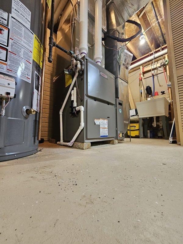 Installed a new 96% efficiency 90,000 BTU upflow gas furnace in the basement mechanical room, ensuring proper leveling and positioning on concrete pavers. Connected white PVC venting system for intake and exhaust, installed a 17-gallon whole-home humidifier, mounted a 5-inch media filter rack with 20x25x5 filter, and programmed a new WiFi-enabled thermostat for remote temperature control and system monitoring.