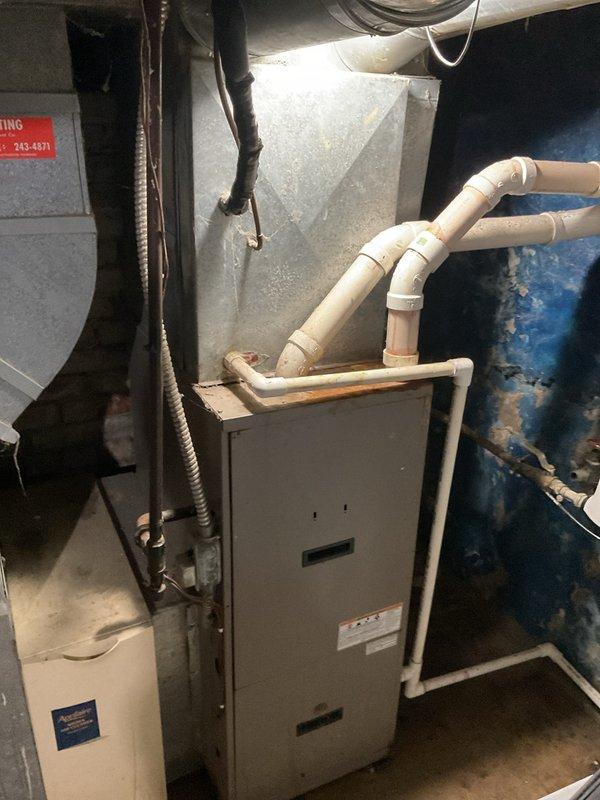 Conducted comprehensive assessment of existing HVAC system for replacement estimate. Evaluated aging furnace unit in basement mechanical room, noting current configuration with PVC condensate and exhaust piping, proximity to water heater, and integration with existing ductwork infrastructure. Documented condition of outdoor air conditioning unit showing significant weathering, accumulated debris on top panel and fan guard, and deteriorated concrete pad with multiple cracks requiring attention during replacement installation.