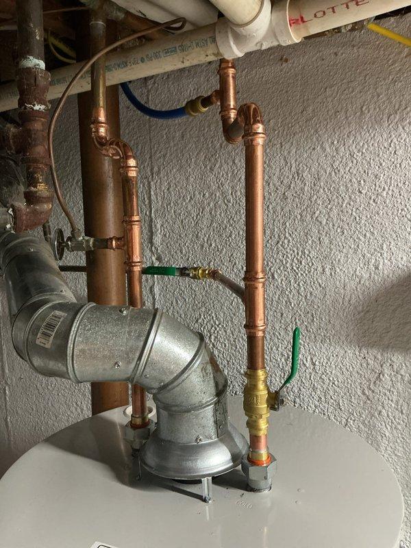 Completed installation of Bradford White natural gas automatic storage water heater with full plumbing connections and safety compliance. Installed copper supply lines with brass fittings, galvanized metal connections, and multiple shut-off valves including green-handled ball valves for water control and system isolation. All connections secured to manufacturer specifications with proper venting configuration and safety labels verified for code compliance.