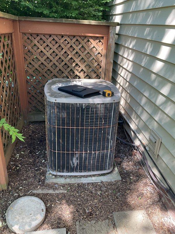 Conducted comprehensive site evaluation of existing HVAC system for complete replacement estimate. Assessed outdoor Amana condenser unit positioned on concrete pad in residential backyard, noting equipment age, condition, and accessibility for replacement. Evaluated indoor Amana furnace and air handler configuration in basement utility area, documenting current system specifications, venting arrangement with PVC exhaust pipes, and ductwork connections. Photographed both outdoor and indoor equipment to document existing installation parameters, clearances, and spatial considerations necessary for accurate replacement system sizing and installation planning.