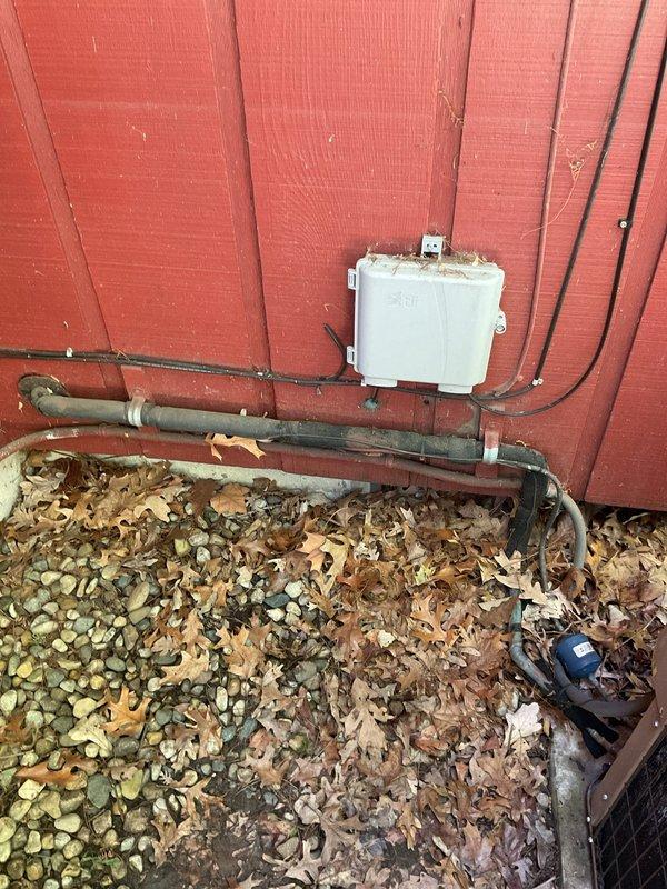 Conducted comprehensive site evaluation of existing outdoor air conditioning condenser unit for replacement estimate. Unit exhibited significant age-related deterioration with heavy dirt and grime accumulation on exterior grille surfaces and casing. Documented current system configuration including copper refrigerant line routing, electrical conduit connections, and junction box placement on building exterior. Assessed installation area conditions including concrete pad integrity, clearance requirements, and accessibility for replacement equipment. Photographed existing unit positioning against building structure and utility connections to ensure proper sizing and placement specifications for new system installation.