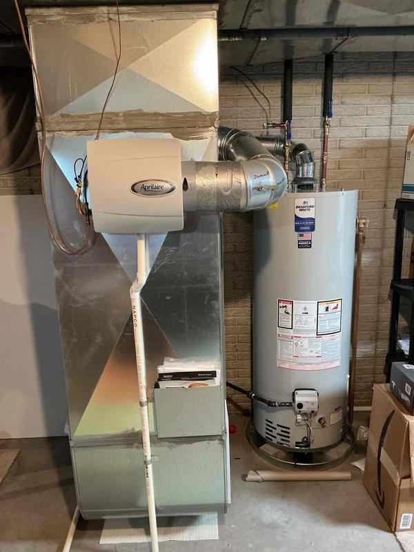 Completed comprehensive tune-up maintenance on residential HVAC system including outdoor condensing unit and indoor equipment. Performed standard inspection procedures, verified proper operation of all components, and documented system condition with photographs showing AC condenser unit, water heater, and Aprilaire humidifier in basement mechanical room.