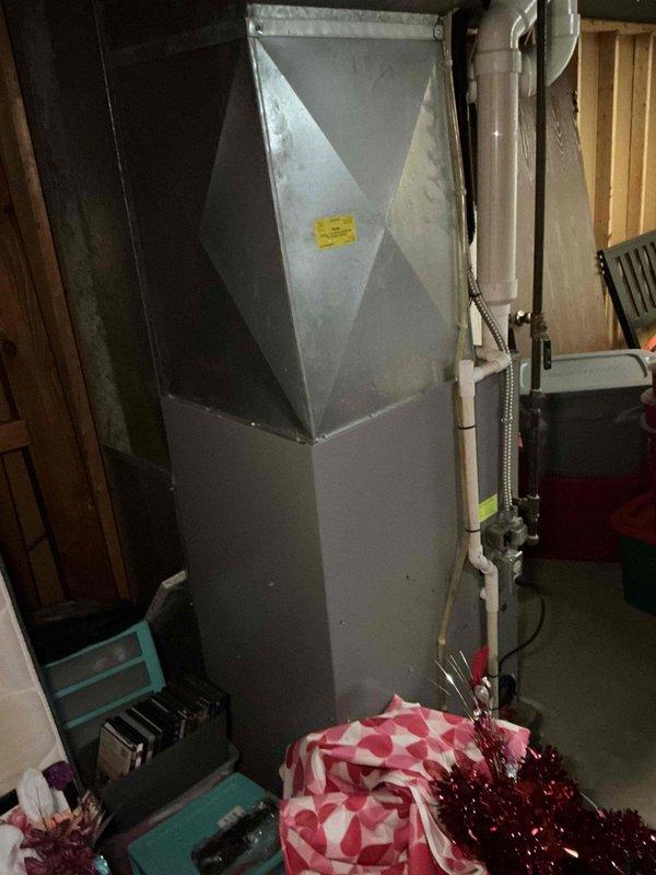 Responded to no cooling complaint on residential air conditioning system. Upon arrival, performed diagnostic inspection of HVAC equipment located in basement utility area. System evaluation completed, findings documented with photographic evidence of furnace unit and associated mechanical equipment including water heater and ventilation components in unfinished basement space.