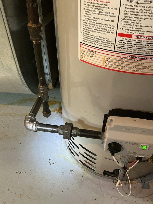 Completed residential water heater replacement in utility room. Removed existing unit and installed new white cylindrical water heater with proper safety labeling and operational specifications. Connected copper supply lines with shut-off valves (red and green handles) to top of unit, installed expansion tank, and secured all brass fittings and connections. Installed gas control valve with indicator light at base of unit, connected flexible gas line, and verified all electrical wiring connections. All plumbing connections tested and confirmed leak-free, unit operational and ready for service.
