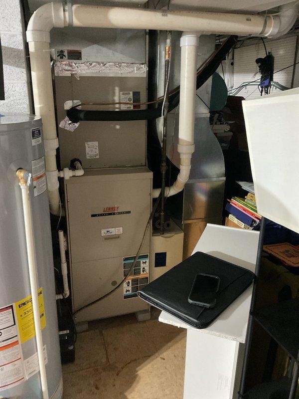 Conducted comprehensive assessment of existing residential HVAC system for complete air conditioning replacement. Evaluated outdoor Lennox condenser unit positioned on gravel pad against house exterior, noting current refrigerant line routing and electrical connections. Inspected indoor basement equipment including existing Lennox furnace and associated ductwork configuration. Documented equipment specifications, system layout, and installation parameters. Provided detailed estimate for new AC system installation including outdoor condenser unit, refrigerant line set, electrical requirements, and integration with existing forced-air heating system.