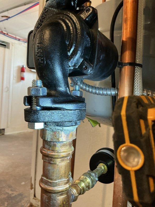 Responded to service call for gas boiler leak at circulation pump connection and within boiler cabinet. Upon inspection, identified active water leak at the pump-to-piping connection point where the circulator interfaces with the brass fittings. Documented existing conditions showing corrosion and patina on brass components and aging flexible connector at pump discharge. Tightened connection points at circulation pump flange and verified integrity of mounting bolts and gasket seal. Inspected boiler cabinet interior for additional leak sources and confirmed moisture presence. Recommended monitoring system pressure and potential replacement of circulator pump and associated fittings due to age-related deterioration of components.