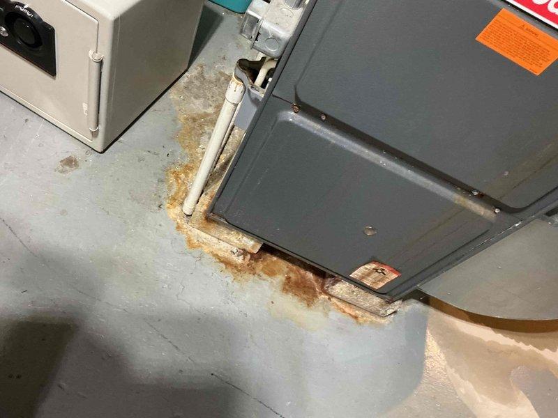 # HVAC Service Call - No Cooling Condition

Responded to service call for Ruud 4-ton central air conditioning system with compressor failing to initialize, resulting in no cooling to entire residence. Unit had not been serviced in several years.

Upon arrival, performed visual inspection of outdoor condensing unit and indoor air handler. Noted significant water damage and rust-colored staining on concrete floor surrounding air handler, indicating potential chronic condensation drainage issues or previous leak. Observed corrosion on equipment base where metal contacts wet concrete surface.

Checked electrical service at breaker panel and verified power supply to AC circuits. Located dedicated air conditioning breakers and confirmed proper voltage. Inspected wiring connections at disconnect and unit terminals for loose connections or damage.

Tested compressor contactor, capacitor, and control circuits. Evaluated thermostat signal and low-voltage control wiring for proper operation. Meas