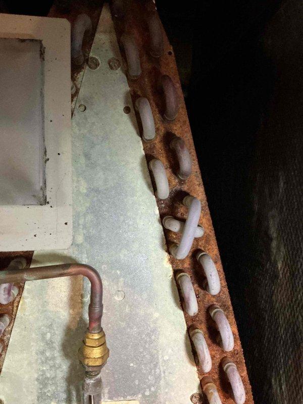 Performed preventive maintenance on a 20+ year old air conditioning system. Conducted visual inspection of evaporator coil assembly using borescope camera to assess internal duct conditions and verified refrigerant line connections. Documented significant corrosion present on copper refrigerant lines and heat exchanger components, indicating prolonged exposure to moisture and age-related deterioration of the system.