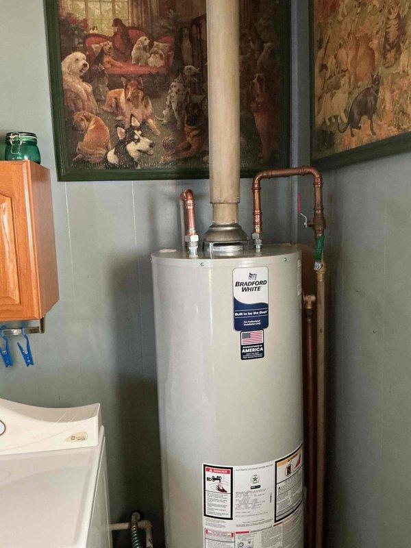Completed warranty replacement installation of Bradford White residential water heater in utility room. Removed existing failed unit and installed new Bradford White water heater with proper venting and gas connections. Connected copper supply lines with brass shut-off valves, ensuring secure hot and cold water distribution. Installed gas control valve assembly and verified all connections for leaks. Tested unit operation and confirmed proper heating function before completion.