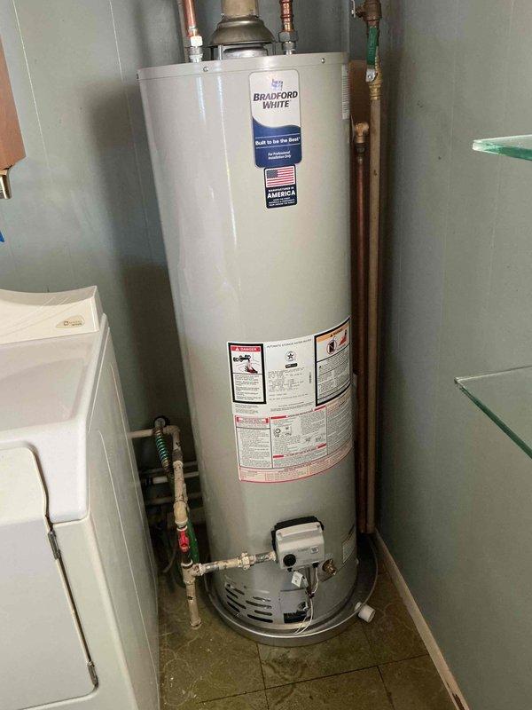 Completed warranty replacement installation of Bradford White residential water heater in utility room. Removed existing failed unit and installed new Bradford White water heater with proper venting and gas connections. Connected copper supply lines with brass shut-off valves, ensuring secure hot and cold water distribution. Installed gas control valve assembly and verified all connections for leaks. Tested unit operation and confirmed proper heating function before completion.