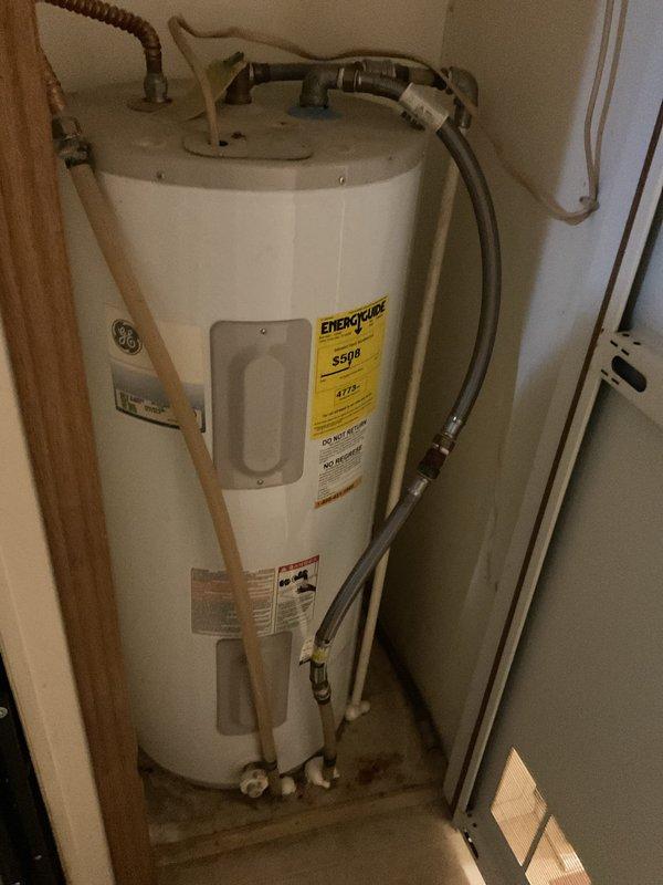 Provided estimate for replacement of existing GE electric water heater in mobile home utility closet. Inspected current unit manufactured in April 2009 with 120/208 volt AC specifications and noted age-related wear requiring full replacement. Documented existing installation including copper supply piping, flexible connectors, and shut-off valves at base connections. Photographed unit specifications, EnergyGuide label showing model S550, and confined workspace conditions for proper sizing and installation planning.