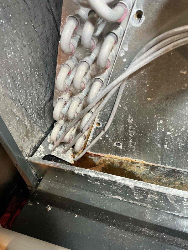 # Leak Search Performed on 10+ Year Old HVAC System

Responded to no cooling complaint on aging HVAC unit. Conducted thorough leak search on refrigerant system due to suspected loss of charge. Inspected evaporator coil assembly and found evidence of corrosion and residue buildup at tube connection points on heat exchanger headers, indicating potential refrigerant leak locations. Documented extensive rust and oxidation on mounting brackets and base pan, consistent with prolonged moisture exposure and age-related deterioration. Examined refrigerant line connections and serpentine coil loops for leak indicators. System components showed significant wear, corrosion, and deterioration typical of units exceeding their expected service life. Photographed findings for documentation purposes. Recommended further evaluation and repair options given the advanced age and condition of the equipment.