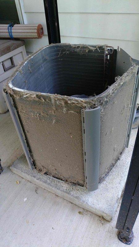 Performed seasonal maintenance inspection on 19-year-old air conditioning system as part of an annual tune-up special. Upon arrival, found outdoor condensing unit in severely deteriorated condition with exterior panels missing and condenser coils heavily clogged with dirt, debris, and dried mud accumulation. Conducted thorough visual inspection of exposed internal components and utilized borescope camera to assess coil condition and verify extent of blockage throughout the heat exchanger fins. Unit's compromised state with missing protective housing and significant debris buildup was documented photographically for service records.